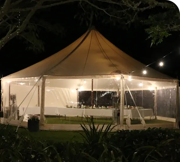 Long tables set for dinner inside a clear-wall marquee at night