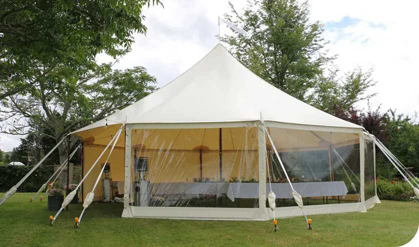 Tables with white linen and chairs set inside a clear-wall marquee in daylight