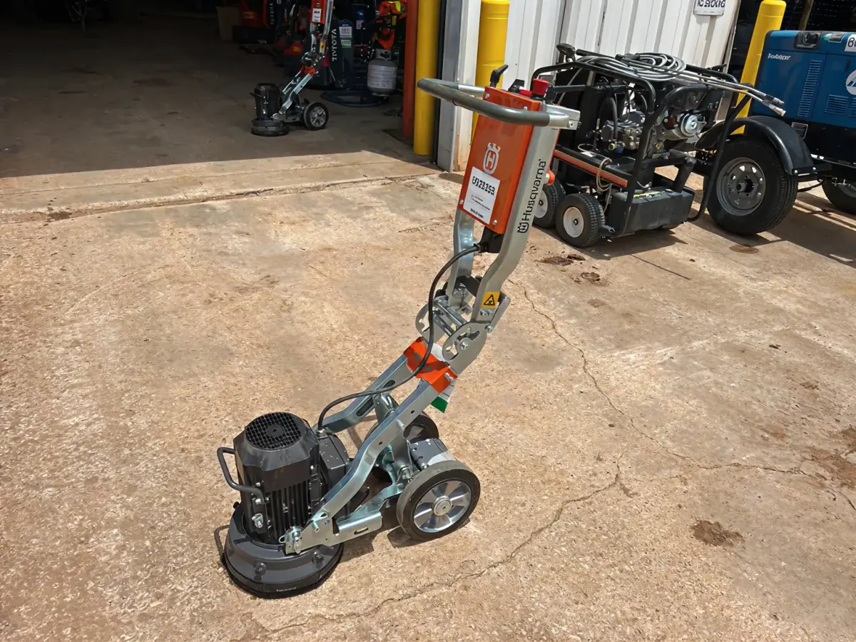 Orange concrete floor grinder on a concrete apron