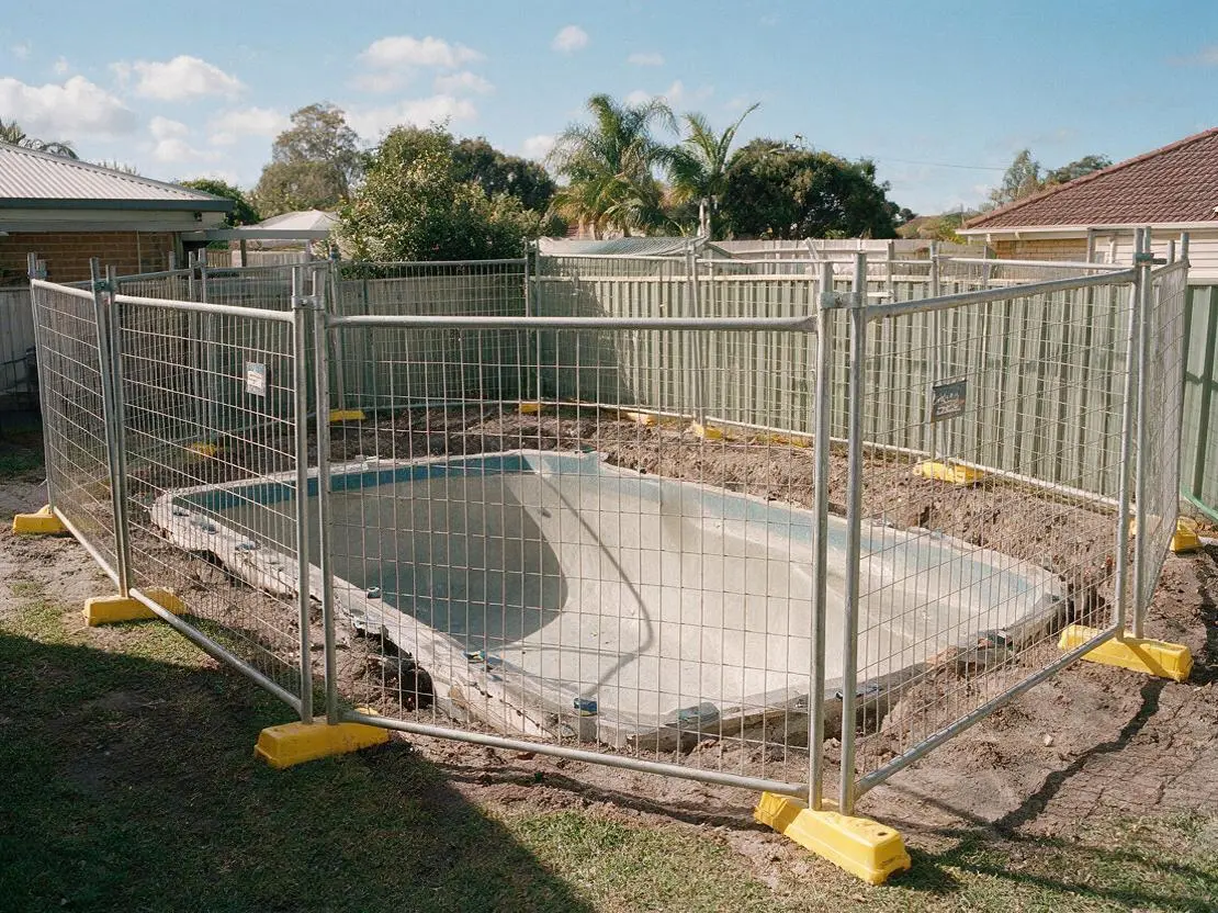 Temporary fencing panels around a backyard swimming pool under construction
