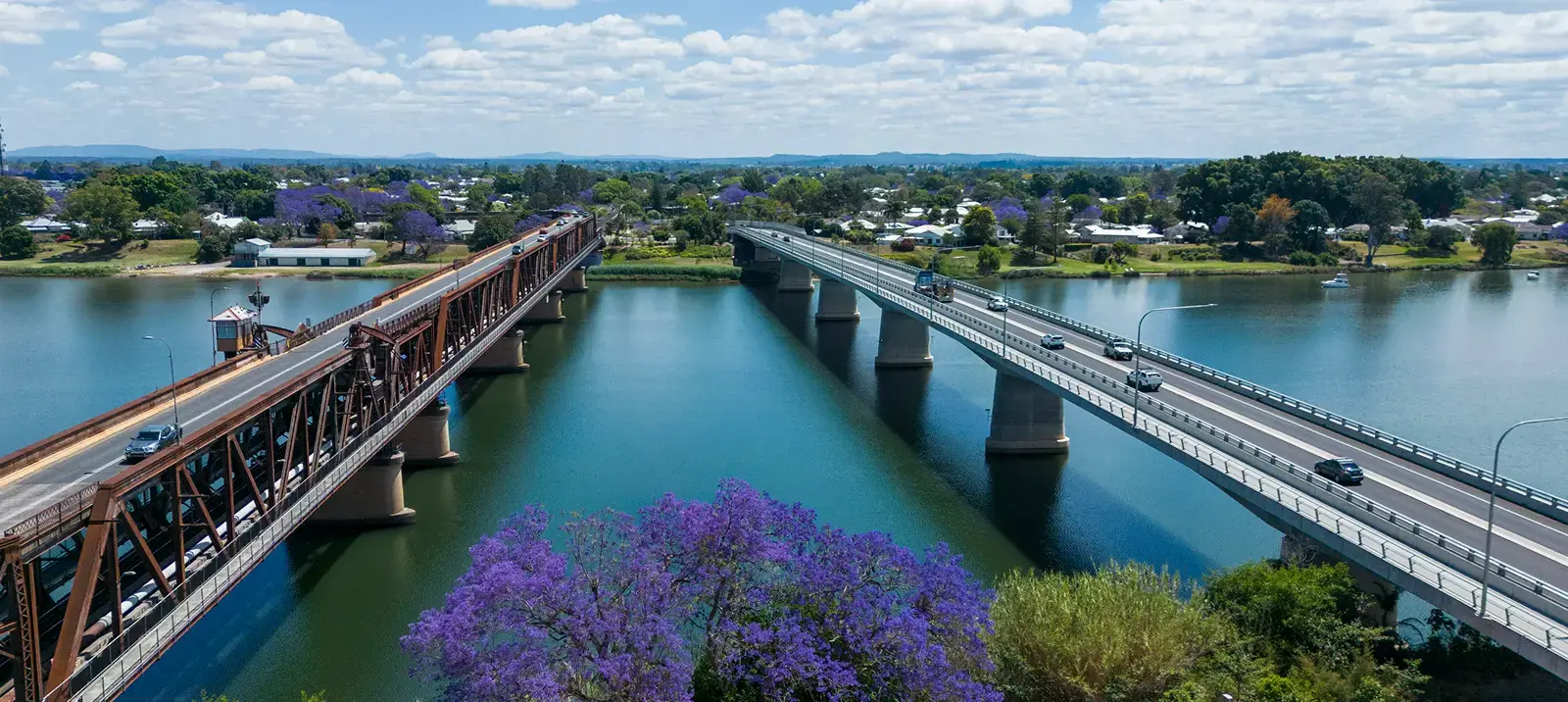 Aerial view of the two Grafton bridges over the Clarence River with jacarandas in bloom along the streets