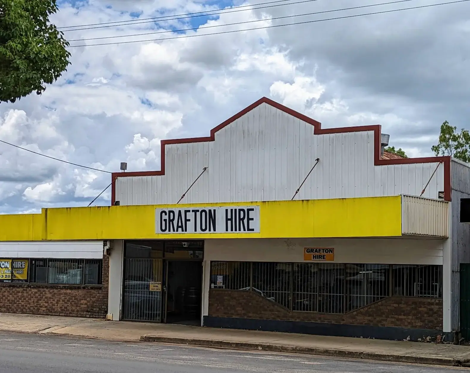 The Grafton Hire shopfront at 71 Spring Street with its white parapet, yellow awning and signage
