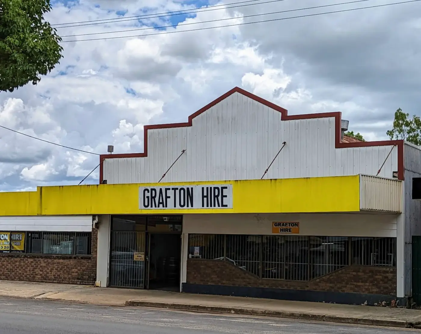 The Grafton Hire shopfront at 71 Spring Street with its white parapet, yellow awning and signage