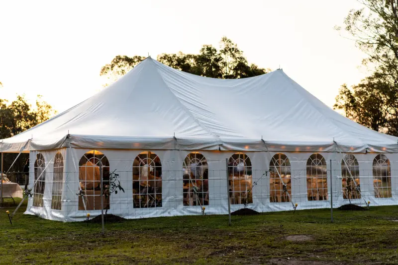 White peg-and-pole marquee with arched windows glowing at sunset on a Clarence Valley property