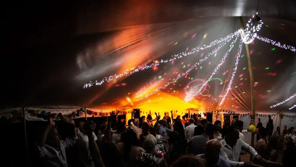 Guests dancing inside a marquee under fairy lights