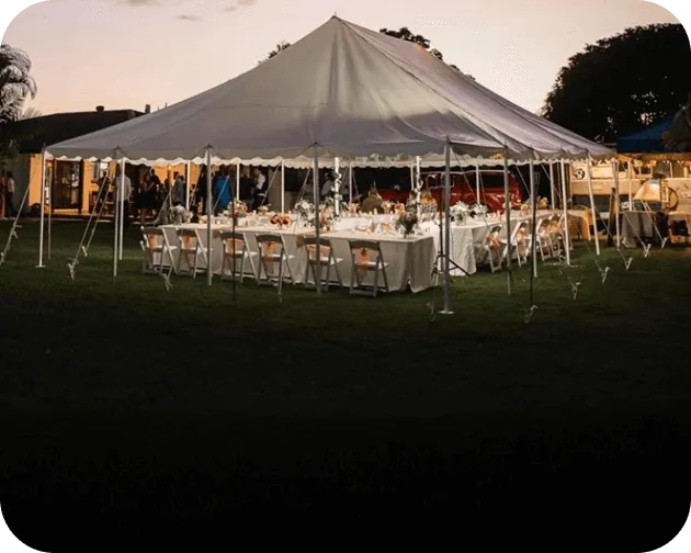 Long tables dressed for dinner inside a marquee at dusk