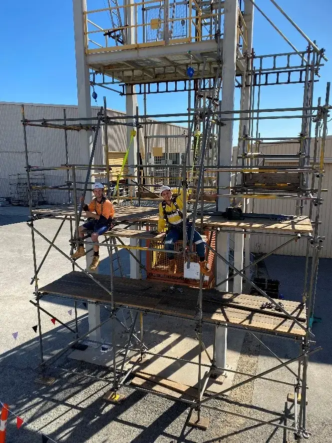 Two workers in hi-vis on a scaffold platform