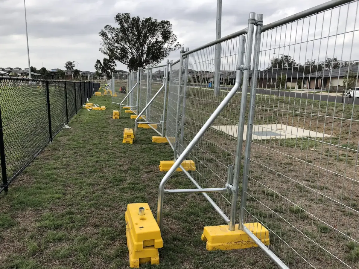 Galvanised temporary fencing panels along a grassy verge