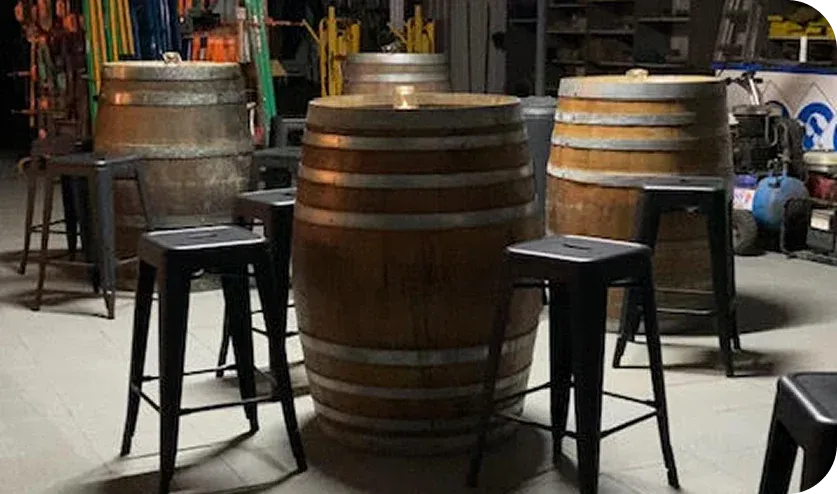 Wine barrels and bar stools set up as a bar inside a shed